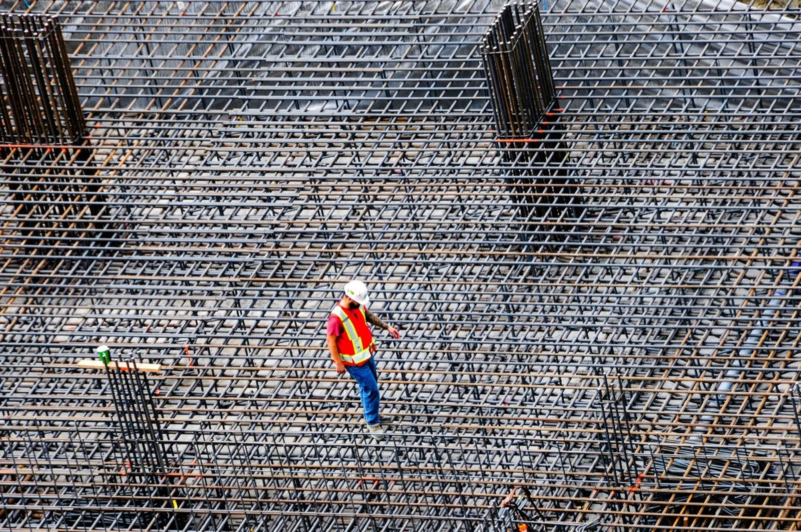 Armeringsnet på en byggeplads set oppefra, med en arbejder i sikkerhedsudstyr