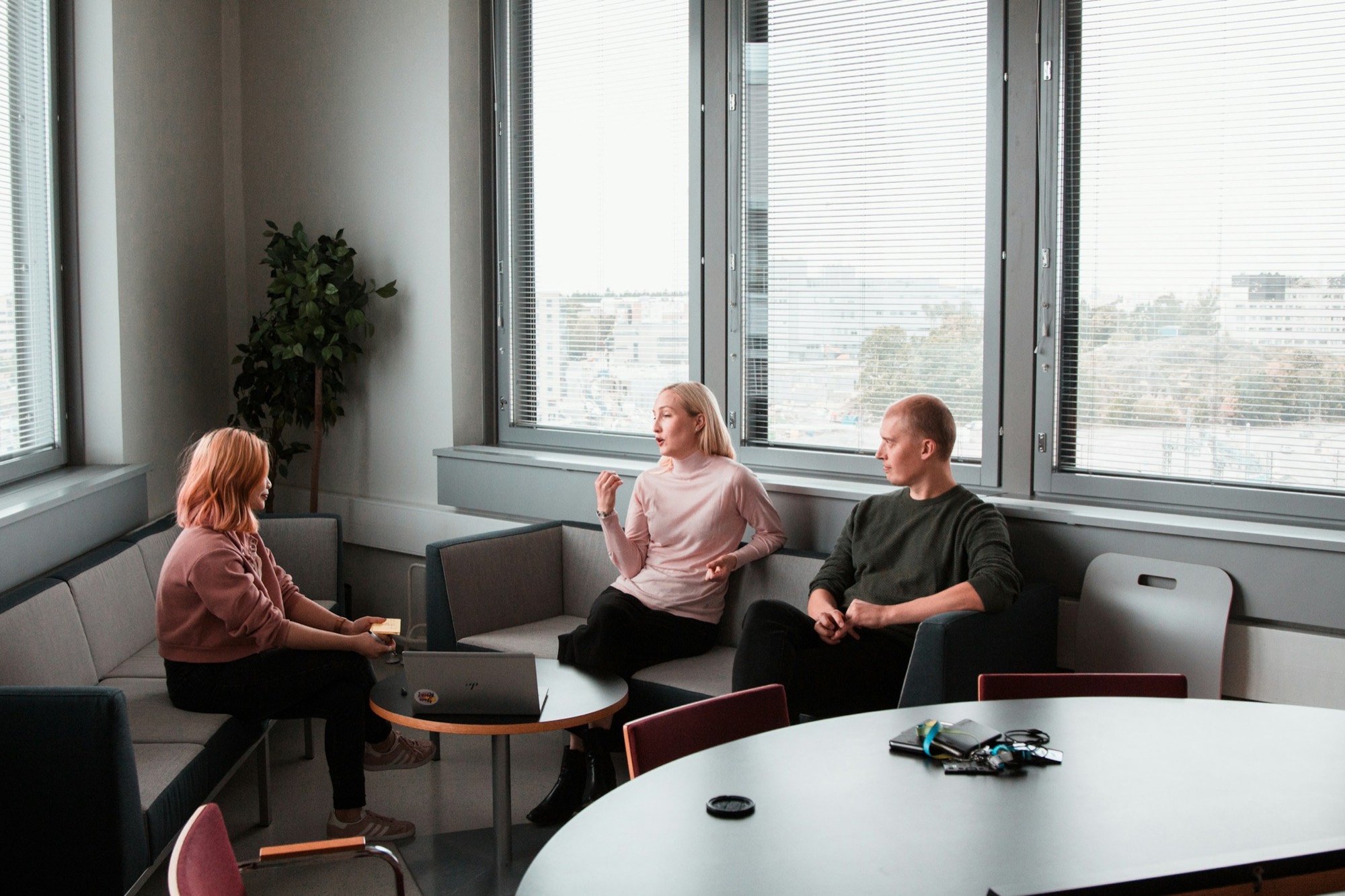 Tre kolleger i samtale i en moderne kontorlounge